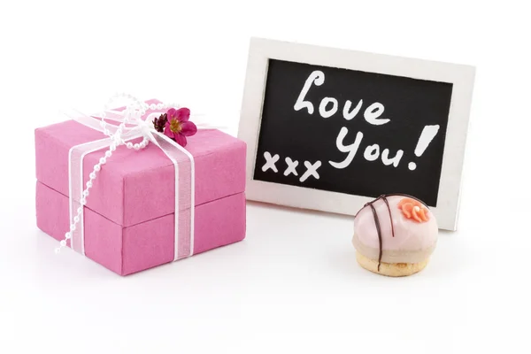Rózsaszín jelen és egy chalckboard a szavakat, "szeretlek" — Stock Fotó