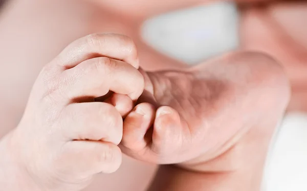 Kleines Baby hält Fuß in Handfläche — Stockfoto