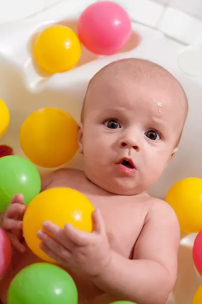 Petit bébé ayant une baignoire avec des boules colorées — Photo
