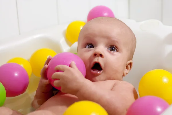 Pequeno bebê tendo um banho com bolas coloridas — Fotografia de Stock
