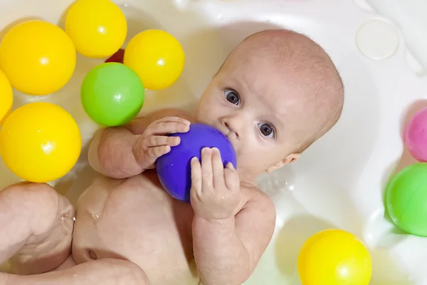 Маленька дитина купається з різнокольоровими кульками — стокове фото