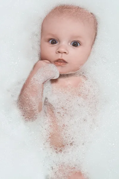 Piccolo bambino che fa il bagno e giace in schiuma bianca — Foto Stock