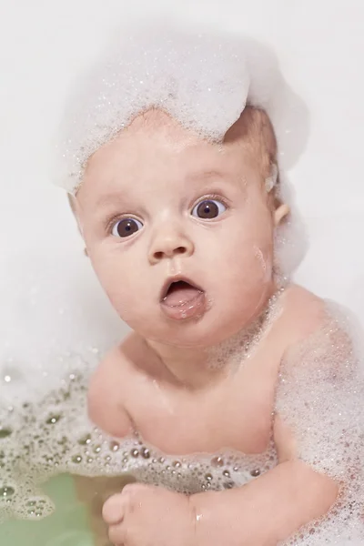 Pequeno bebê tendo um banho e sentado em espuma branca — Fotografia de Stock