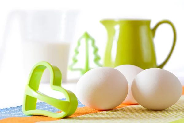 Cookies making: fresh eggs, green jug, milk and cookie forms iso — Stock Photo, Image