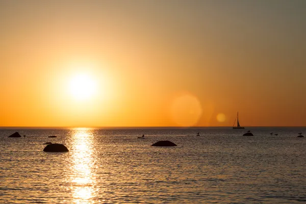 Boot silhouet in de zee en de zon fakkels — Stockfoto