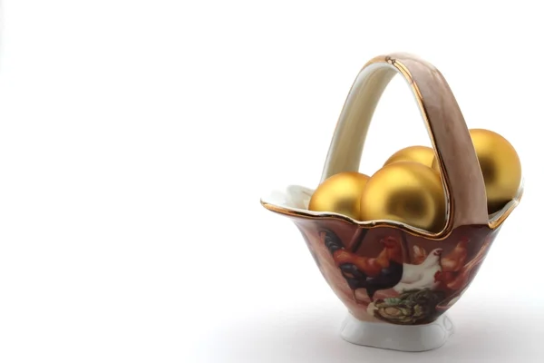 Golden egg in porcelain basket on white background — Stock Photo, Image