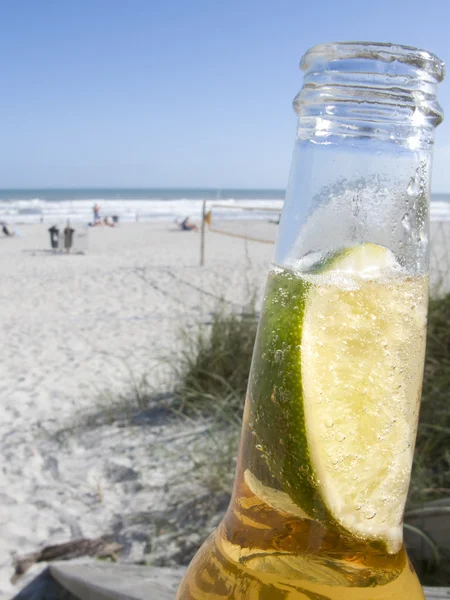 Garrafa de cerveja com limão na praia — Fotografia de Stock