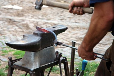 The smith forges a horseshoe clipart