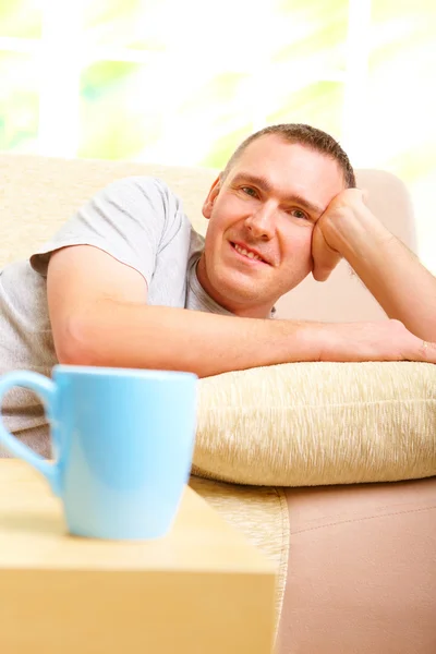 Man relaxing on sofa with cup — Stock Photo, Image