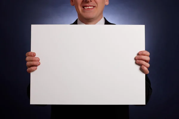 Hombre de negocios sonriente sosteniendo una gran tarjeta en blanco — Foto de Stock