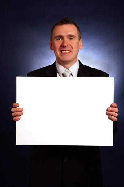 Empresário sorridente segurando um grande cartão em branco — Fotografia de Stock
