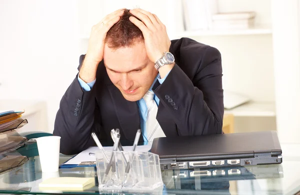 Стрессовый бизнесмен сидит за столом — стоковое фото