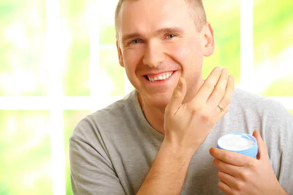 Homem aplicando creme facial — Fotografia de Stock