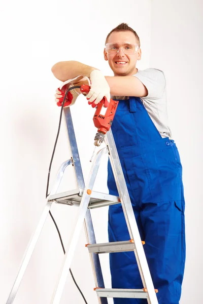 Mann mit Bohrer steht auf Leiter — Stockfoto