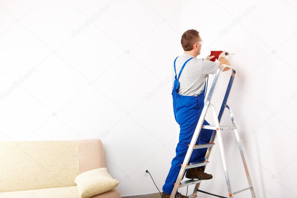 Man with drill working on ladder