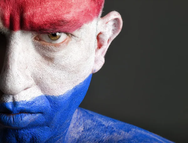 Man with his face painted with the flag of Netherlands