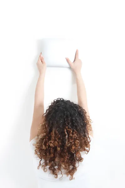 Молодая женщина держит планшетный компьютер на стене - вид сзади - whi Стоковая Картинка