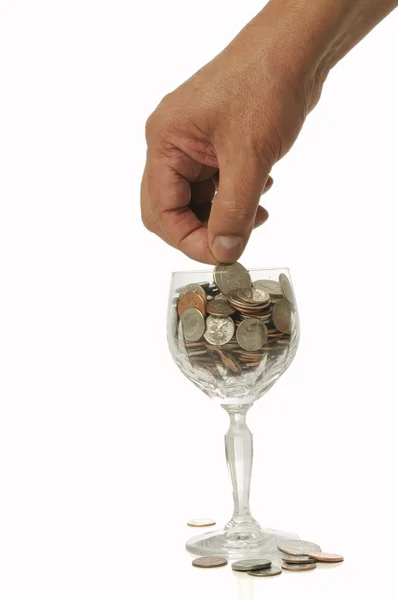 Hand placing coin in glass — Stock Photo, Image