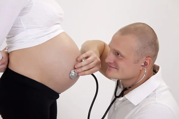 怀孕。医生用听诊器听病人. — 图库照片