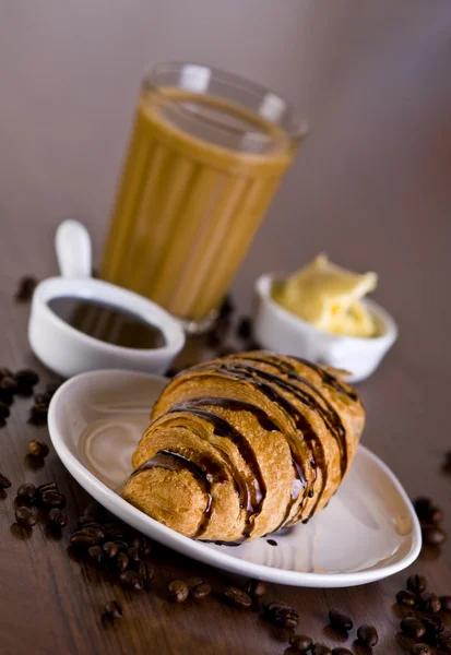 Croissant mit Schokolade und einem Glas Kaffee — Stockfoto