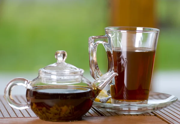 Glass of tea with teapot — Stock Photo, Image