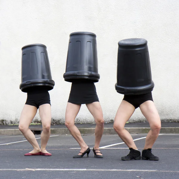 Três latas de lixo cobrem três mulheres cabeças — Fotografia de Stock