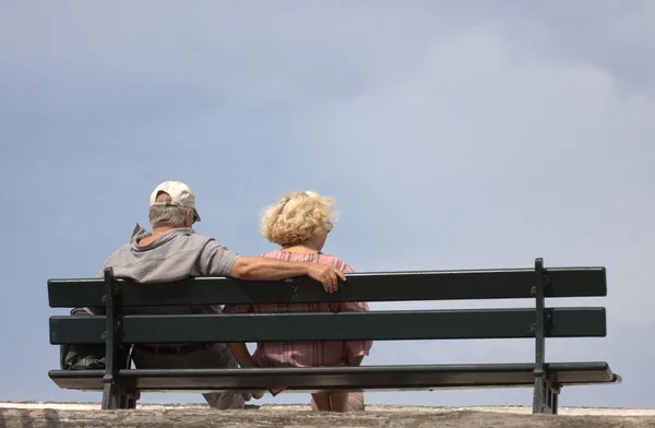 坐在长凳上的老年夫妇 免版税图库图片