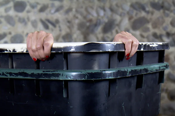 Vrouw gaat gluren uit een container vuilnis. — Stockfoto