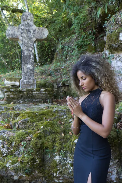 Kobieta modli się obok krzyż kamienny. — Zdjęcie stockowe