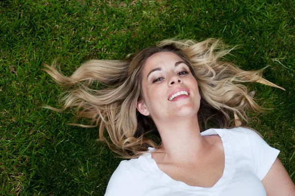Jovem menina feliz deitado na grama — Fotografia de Stock