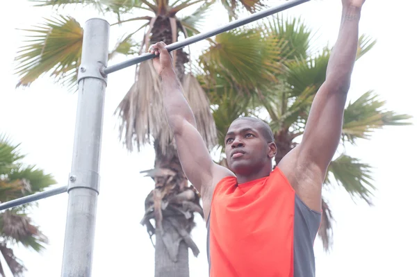 Portrait of an African American athlete doing pullups — Stock Photo, Image
