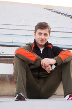 Male athlete sitting in the bleachers clipart