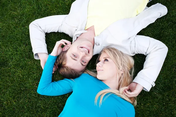 Jovem casal apaixonado deitado na grama — Fotografia de Stock