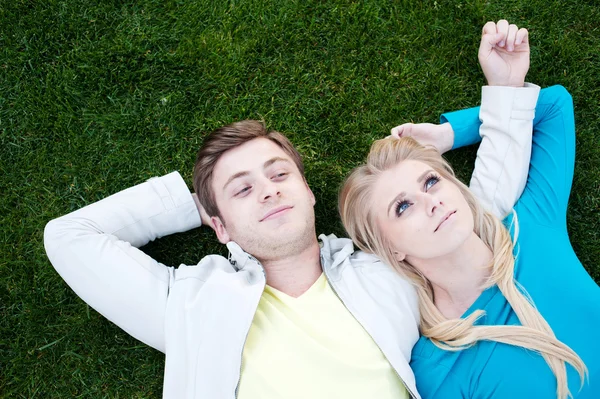 Jong paar in liefde liggen in gras — Stockfoto