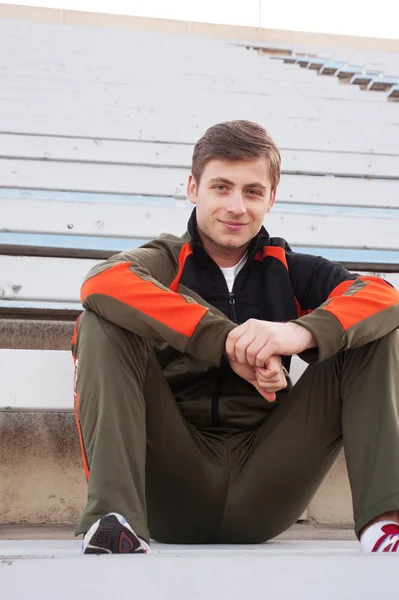 Male athlete sitting in the bleachers — Stock Photo, Image
