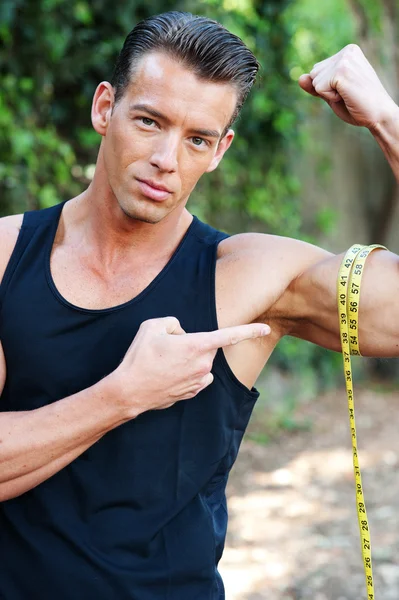 Hombre muscular midiendo bíceps — Foto de Stock