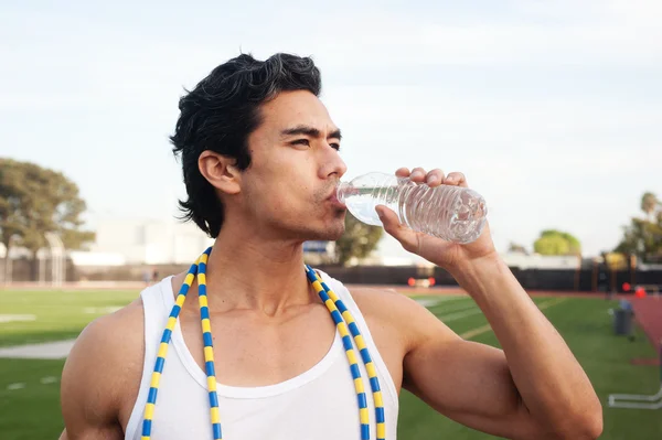 Schöner, junger Latino-Athlet trinkt Wasser — Stockfoto