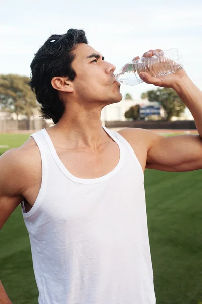 Handsome, young latino athlete drinking water — Stock Photo, Image