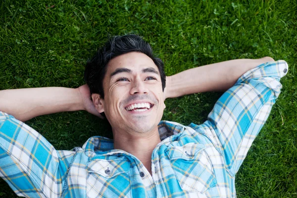 Młody człowiek szczęśliwy, leżąc na trawie — Zdjęcie stockowe