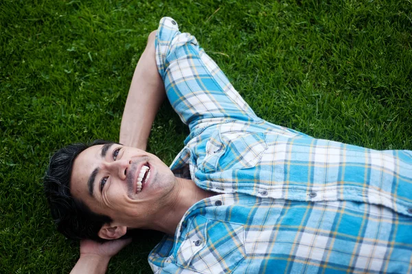 Jovem feliz deitado na grama — Fotografia de Stock