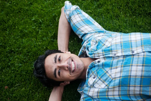 Gelukkig jonge man liggen in het gras — Stockfoto