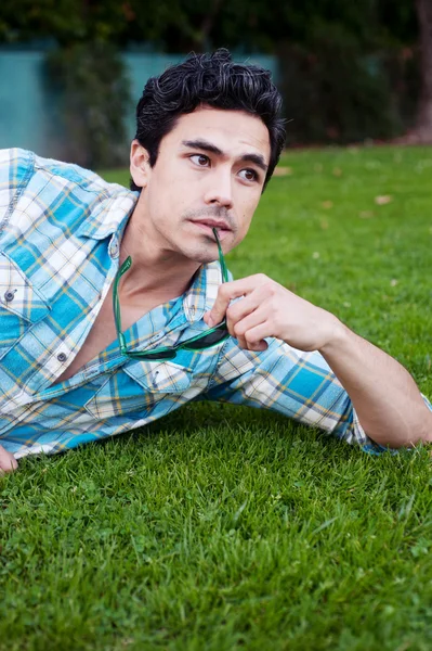 Schöner junger Mann liegt im Gras — Stockfoto