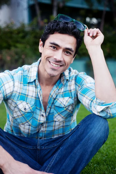 Handsome young man sitting in the grass — Stock Photo, Image