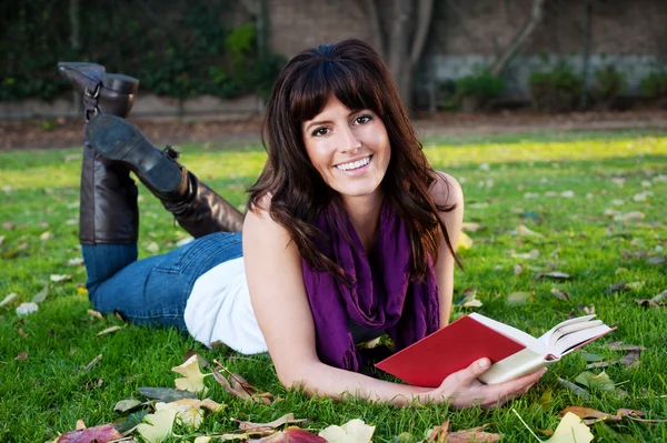 Красива дівчина читає книгу в траві — стокове фото