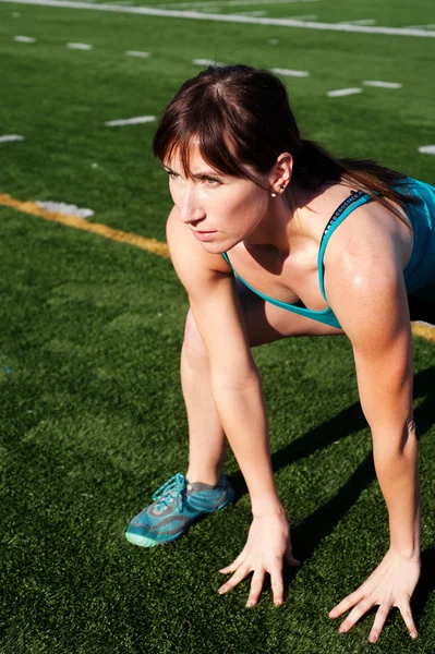 Female athlete stretching on field — Stock Photo, Image