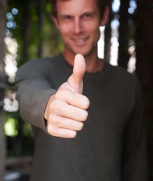 Young man giving a thumbs up hand gesture — Stock Photo, Image