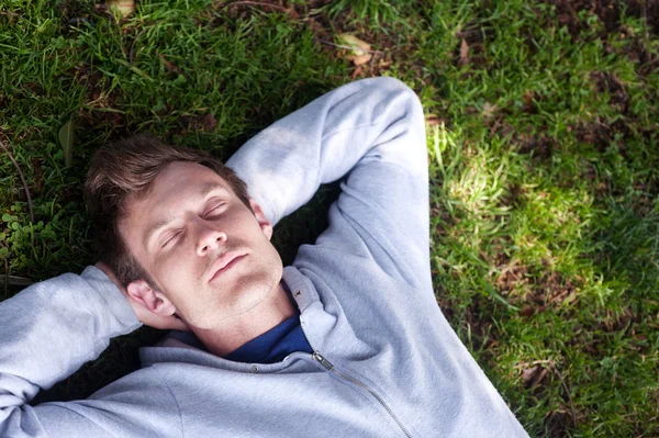 Pohledný mladý muž spí v trávě — Stock fotografie