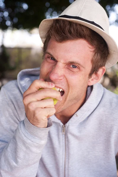 Podobizna mladého muže kousat jablko — Stock fotografie