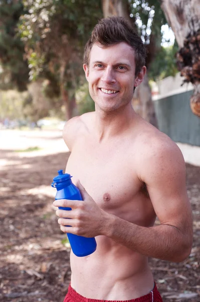 Portrait of a young athletic runner outside with water bottle — Stock Photo, Image