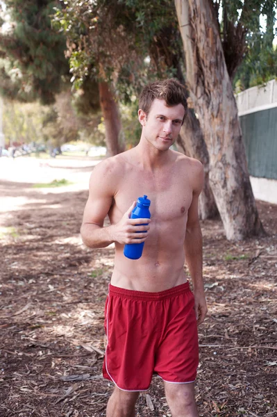 Portret van een jonge atletische loper buiten met water fles — Stockfoto